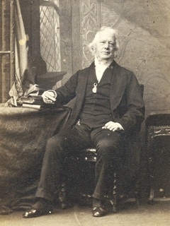 Photograph of the Revd Henry Venn Elliott seated at his desk. 